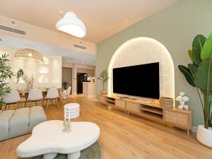 a living room with a flat screen tv and a table at Wabi-Sabi Style Fountain-View 4 BR Apt in the Sky in Dubai