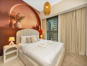 a bedroom with a large white bed with a window at Wabi-Sabi Style Fountain-View 4 BR Apt in the Sky in Dubai