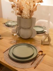 a wooden table with a plate and a vase with flowers at Wabi-Sabi Style Fountain-View 4 BR Apt in the Sky in Dubai