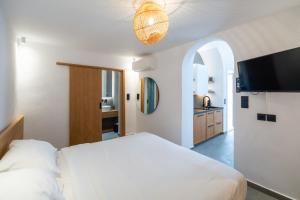 a bedroom with a bed and a flat screen tv at Skepi Town Houses in Mýkonos City