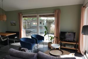 a living room with a couch and chairs and a television at Vakantie huis aan het water in Rijpwetering