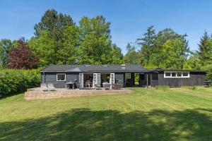 a black house with a patio and a yard at Lovely Secluded Cottage In Dronningmølle in Dronningmølle