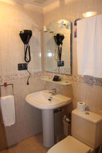 a bathroom with a sink and a toilet and a mirror at Hotel Valdés in Gijón