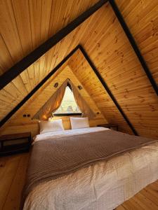 a bed in a wooden room with a window at Outdoor Cottages Kazbegi in Stepantsminda