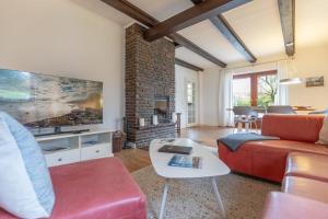 a living room with a red couch and a fireplace at Dat Reethuus in Böhl