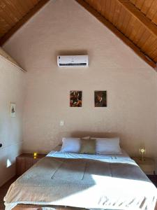 a bedroom with a large bed with two pictures on the wall at Chalé Suíco Nupcial III - Chalés Belo Monte in Pacoti