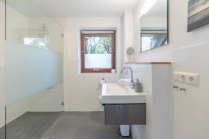 a white bathroom with a sink and a mirror at Dat Reethuus in Böhl +32 photos