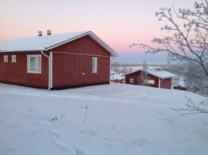 a red barn with snow on the ground at Lomamaja Pekonen Apartments in Muonio