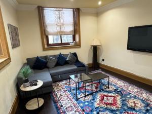 a living room with a couch and a flat screen tv at 2-Bed Cottage Sleeps 4 10 mins to Glasgow Centre in Glasgow