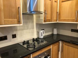 a kitchen with a stove top oven and wooden cabinets at 2-Bed Cottage Sleeps 4 10 mins to Glasgow Centre in Glasgow