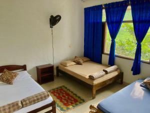 ノカイマにあるPioneros Campestreのベッドルーム1室(ベッド2台、青いカーテン付きの窓付)