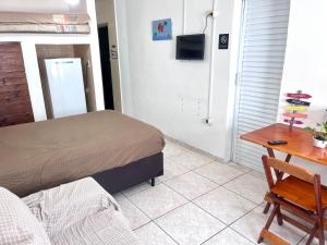 a bedroom with a bed and a desk and a table at Kit do ALEX - AVIAÇÃO - a uma esquina da praia - Ar Condicionado in Praia Grande