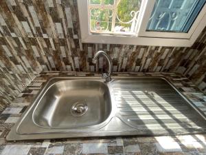 a stainless steel sink in a kitchen with a window at Seven Apartments in Serekunda +28 photos