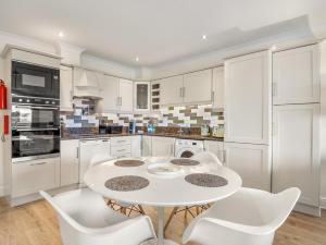 a white kitchen with a white table and chairs at 4 Harbour Heights in Clifden
