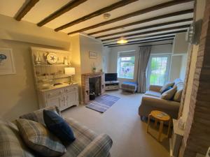 a living room with a couch and a fireplace at Norfolk Chapel Cottages in Docking