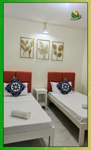 2 Betten in einem Zimmer mit Gemälden an der Wand in der Unterkunft Homey 2BR Apartment with Essentials & Modern Decor - Richkizz in Puerto Princesa