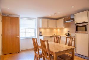 a kitchen with a wooden table and some chairs at CS Exclusive Apartments of Princess Street West End in Edinburgh