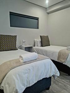 a hotel room with two beds and a tv at Montagu Villa 2 in Mossel Bay