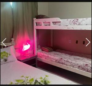 1 Schlafzimmer mit 2 Etagenbetten und einer rosa Lampe in der Unterkunft casa da maria in Cabo Frio