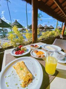 ein Tisch mit Tellern voller Essen und einem Glas Orangensaft in der Unterkunft Enotel Porto de Galinhas All Inclusive in Porto De Galinhas