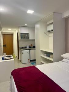 Un dormitorio con una cama blanca y una cocina. en Cupe Porto de Galinhas - Cupe Exclusive 407, en Porto de Galinhas