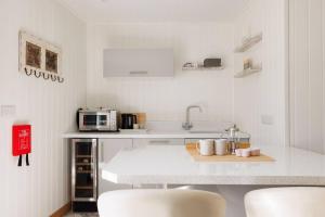 a white kitchen with a counter and white appliances at Cosy Cabin Retreat Close to Beaches in Birdham