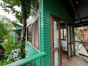 a green house with a tree on the porch at Casa Saíra in Bombinhas