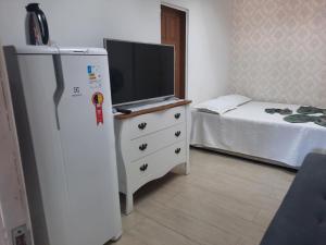 a room with a refrigerator and a tv on a dresser at Mini Casa independente no bairro Praia das Gaivotas in Vila Velha