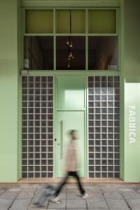 a person walking in front of a green building at Fabrica PlayLoft in the City Center by BiNoBi! in Thessaloniki