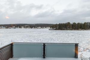 a view of a frozen lake with snow and trees at Northern Lights River Nest in Rovaniemi