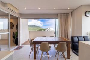 Un comedor con mesa y sillas y una gran ventana. en Apartamentos com Piscina em Floripa - CAC, en Florianópolis