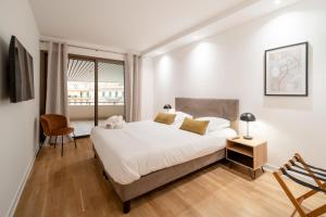 une chambre avec un grand lit blanc et une chaise dans l'établissement 1958 - Luxury apartment Gray Albion - 100m Palais, à Cannes 4 autres photos