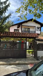 a house with a black gate and a fence at Къща за Гости БАРБЕЛ in Golyam Izvor