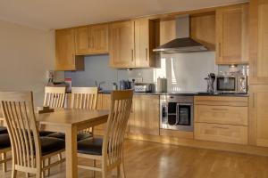 a kitchen with wooden cabinets and a wooden table and chairs at No10 The Links Apartment, Brora in Brora