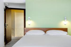 Un dormitorio con una gran cama blanca con dos almohadas. en The Wave House - Seaside Haven, en Jardim do Mar