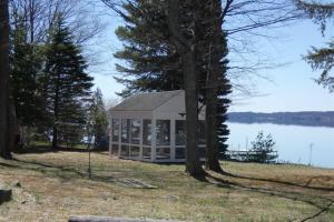 a house on the shore of a lake with trees at South Cottage on Torch Lake in Alden