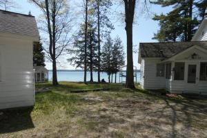 a white house with trees in front of the water at South Cottage on Torch Lake in Alden +19 photos
