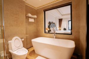 a bathroom with a tub and a toilet and a mirror at Bao An Hotel Hung Yen in HÆ°ng YÃªn +28 photos