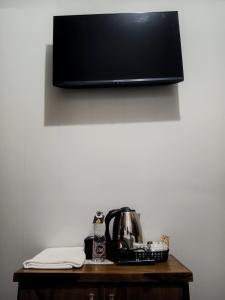 a table with a tea kettle and a tv on a wall at Indah Damai Cottages in Sidomukti