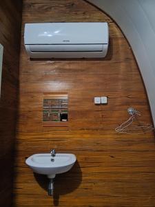 a bathroom with a sink and a air conditioner at Indah Damai Cottages in Sidomukti