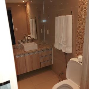 a bathroom with a toilet and a sink and a mirror at Dellos Apart Hotel e Administração LTDA in Brasília +59 photos
