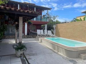 une piscine avec des chaises et une maison dans l'établissement casa da maria, à Cabo Frio