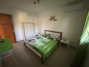 a bedroom with a bed with a green comforter at Les Âmes-Claires 2 in Terre-de-Haut