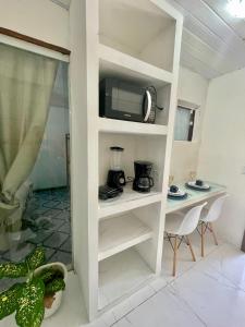 une étagère blanche avec un four micro-ondes et une table dans l'établissement Loft de Praia in Búzios - 10 min a pé da Rua das Pedras, à Búzios