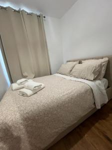 Una cama blanca con dos toallas encima. en APPARTEMENT AU CŒUR DE MARAIS DANS CENTRE de PARIS, en París