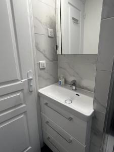 Un baño blanco con lavabo y espejo. en APPARTEMENT AU CŒUR DE MARAIS DANS CENTRE de PARIS, en París