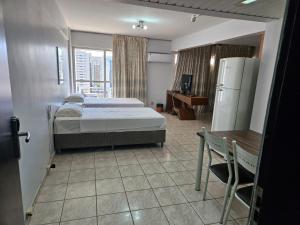 a bedroom with a bed and a table and a refrigerator at Dellos Apart Hotel e Administração LTDA in Brasília