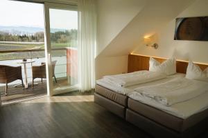 um quarto com uma cama e uma varanda com uma mesa em Gasthof Brennerei zum Forst em Kressbronn am Bodensee