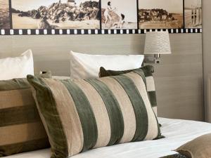 a bed with a green and white striped pillow on it at Best Western Les Bains Hotel et SPA in Perros-Guirec