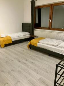 two beds in a room with wooden floors at Helle 4 Zimmer, Küche, Bad, WLAN, 24-7, Parkplatz, 4-10 Personen in Landshut